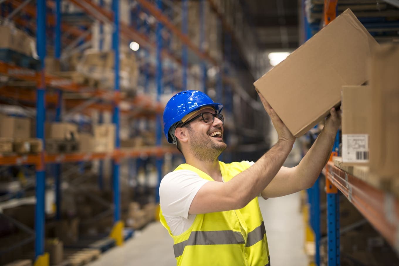 Trabajador de almacen sonriente moviendo cajas en un estante
